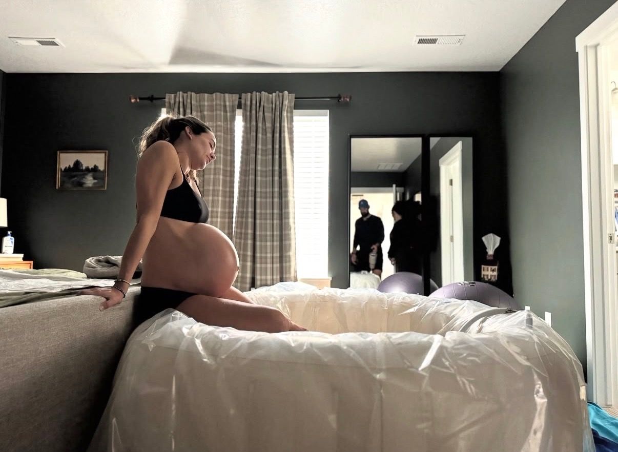 A mother laboring at home beside the birth pool set up in her bedroom