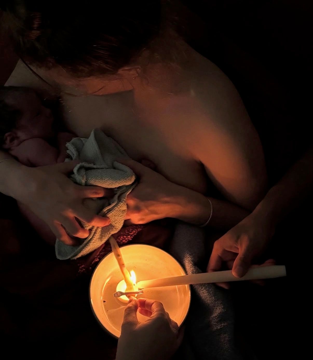 A candlelit cord burning ceremony as a mother holds her newborn skin to skin